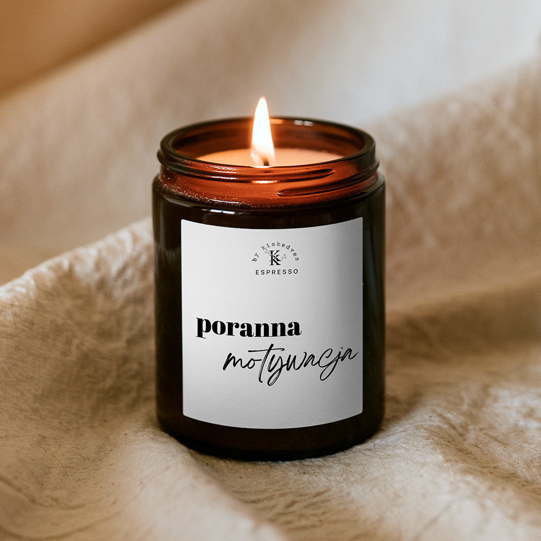 Płonąca świeca sojowa Kiskedves w brązowym słoiczku, na etykiecie napis „poranna motywacja” i monogram Kiskedves Espresso.
