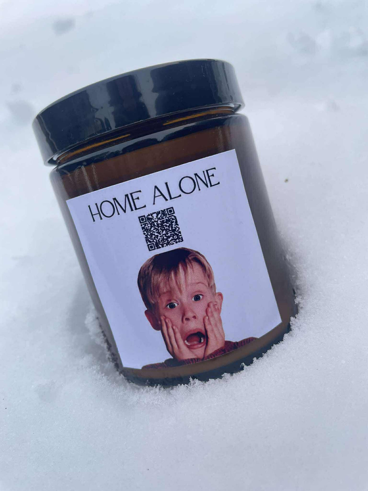 Świąteczna świeca „Melodyjna” Kiskedves na śniegu, na etykiecie kod QR i napis Home Alone