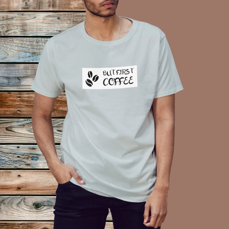 Koszulka Kiskedves But first coffee z czystym napisem BUT FIRST COFFEE i dwoma ziarnami kawy, w kadrze, w zbliżeniu.