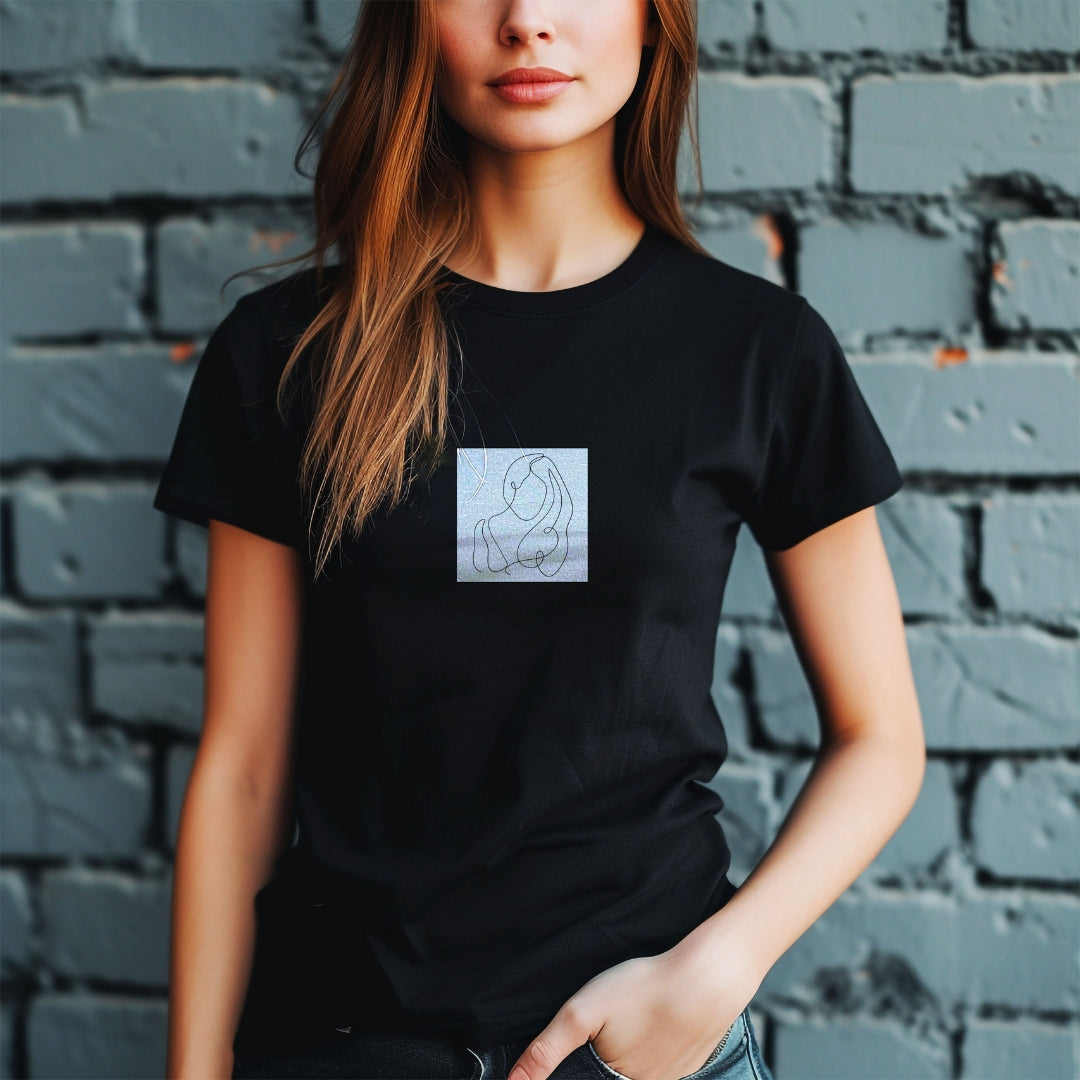 Czarna koszulka Kiskedves Line Art ze splecionymi postaciami, na modelce przed ceglaną ścianą.