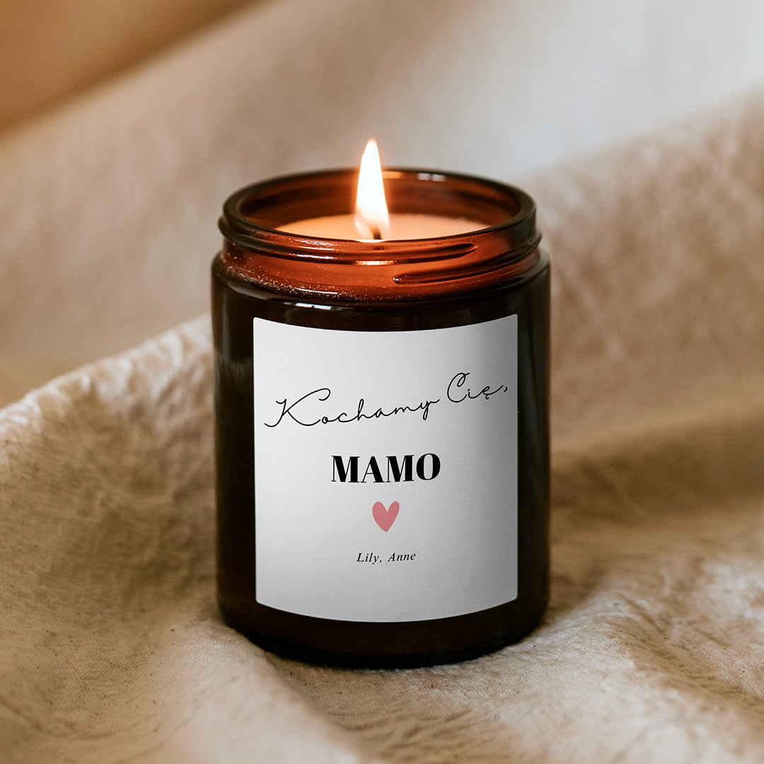 Płonąca świeca sojowa Kiskedves w brązowym słoiczku, na etykiecie napis: „Kochamy Cię, MAMO”, pod nim serduszko i imiona dzieci.