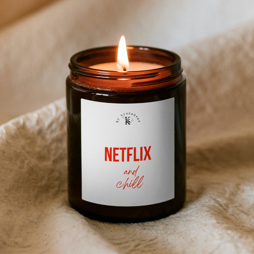Świeca sojowa Kiskedves Netflix and chill w brązowym słoiczku, z płonącym płomieniem, na miękkim kocu.