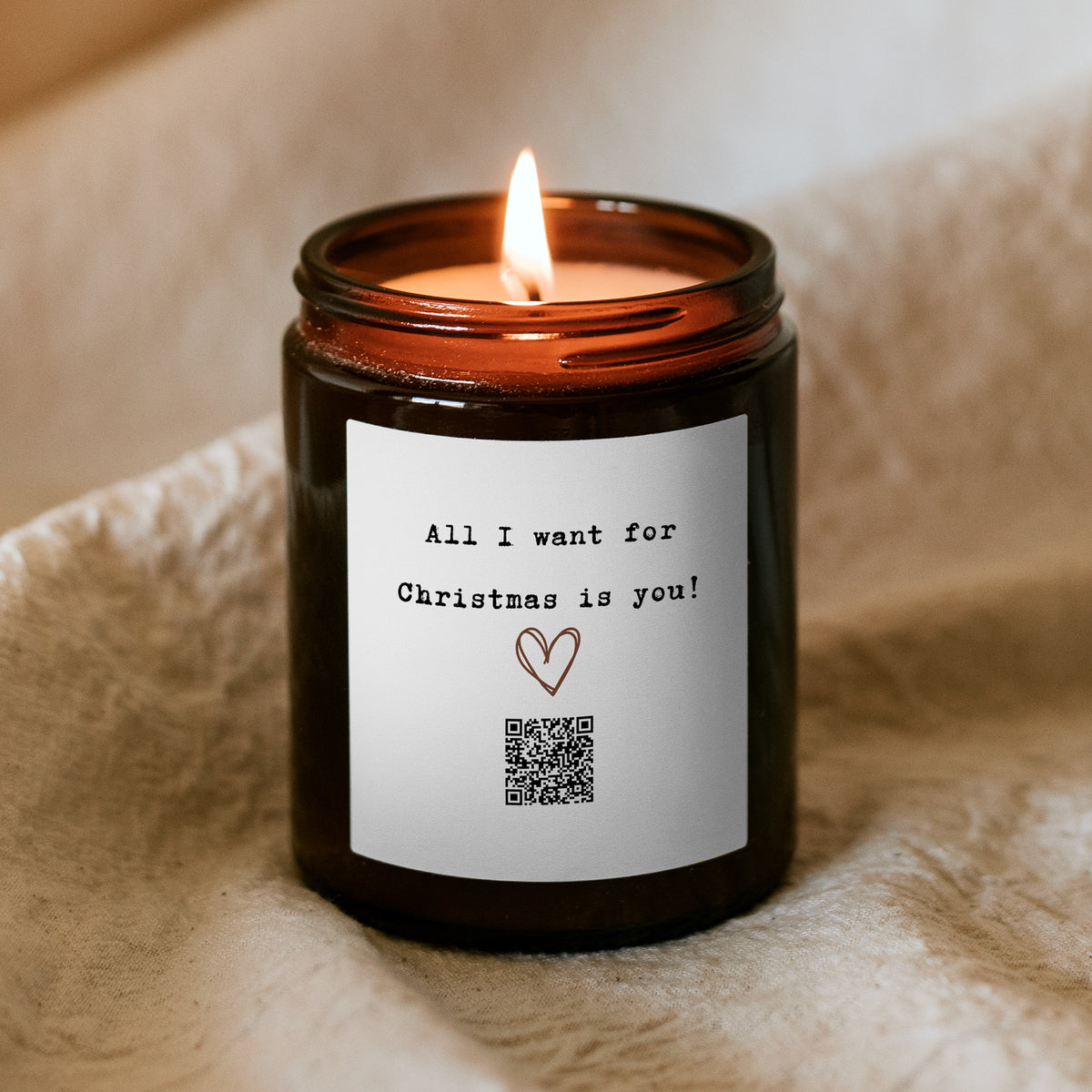 Płonąca świąteczna świeca „Melodyjna” Kiskedves, na etykiecie rysowane serce, kod QR i napis All I want for Christmas is you