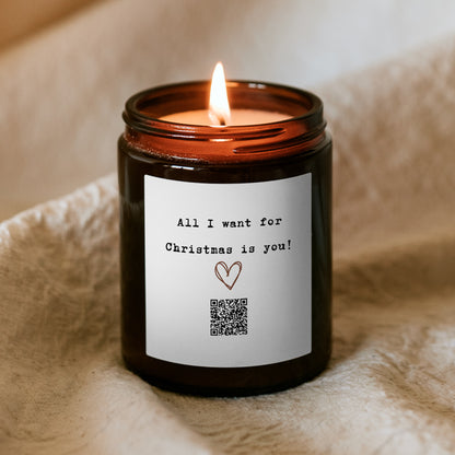 Płonąca świąteczna świeca „Melodyjna” Kiskedves, na etykiecie rysowane serce, kod QR i napis All I want for Christmas is you