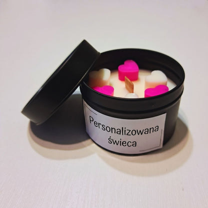 Otwarta czarna metalowa puszka ze świecą sojową, różowymi i białymi woskowymi serduszkami i drewnianym knotem, z etykietą „Personalizowana świeca”